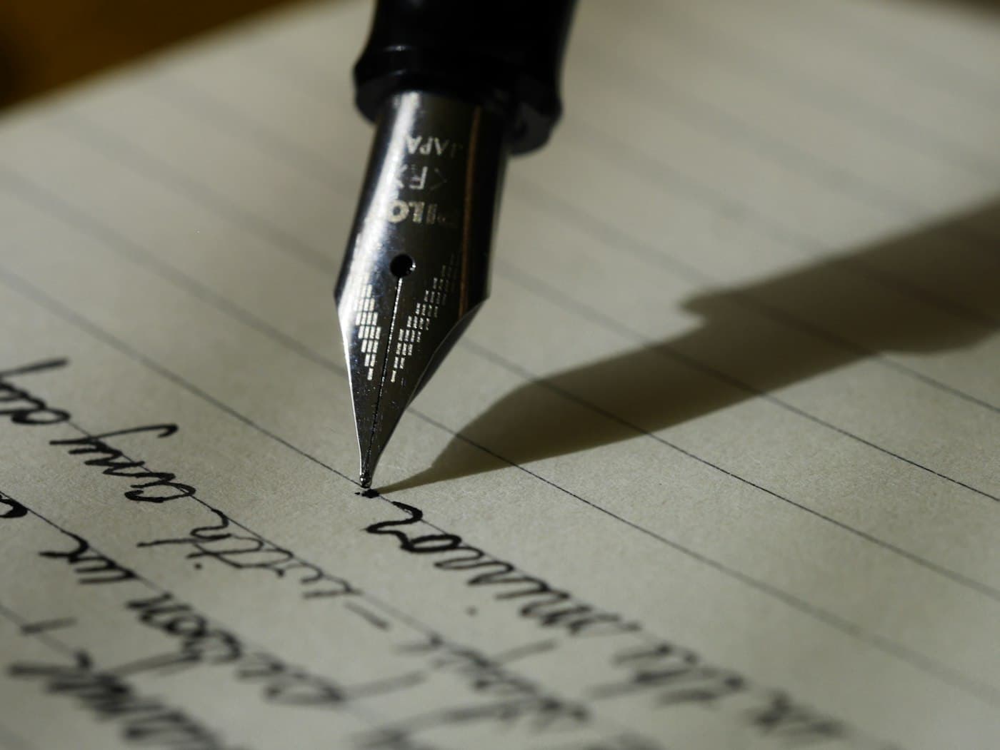 Fountain pen writing on lined paper beside a cup of coffee